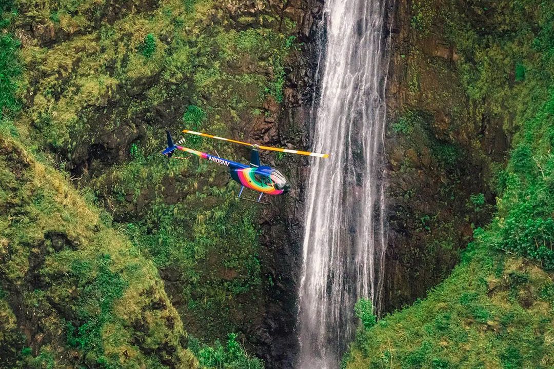 a colorful helicopter next to a waterfall