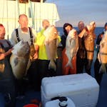 a group of people standing next to a person holding a fish