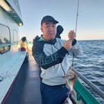 Gene Hong holding a fish on a boat