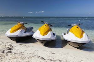 a row of three yellow Waverunners parked on the beach