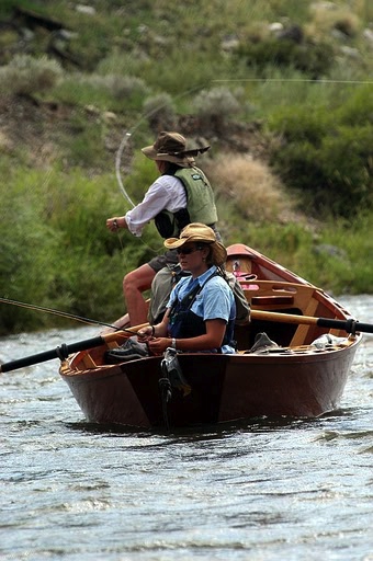 a person riding on the back of a boat next to a river