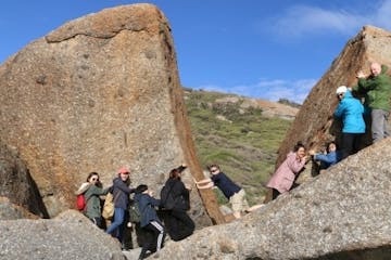 a group of people standing in front of a large rock