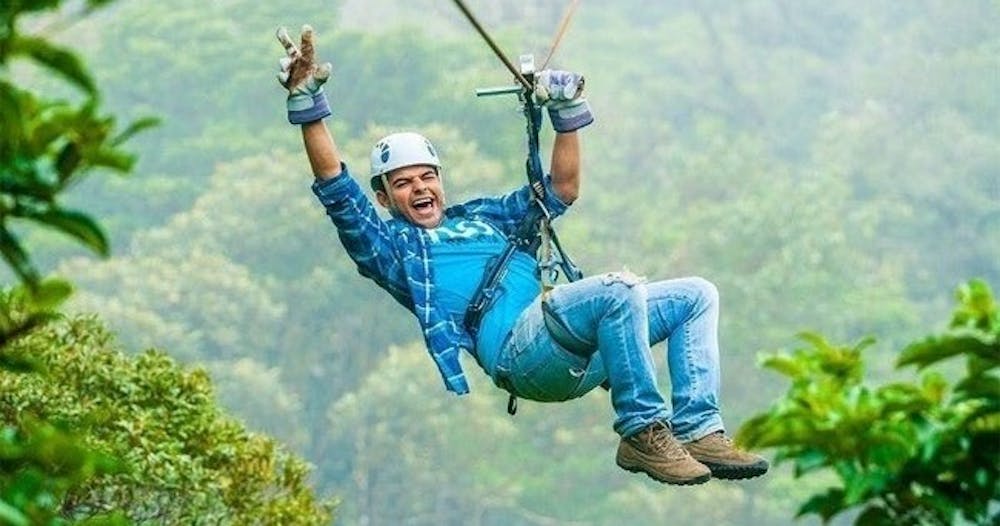 un hombre volando en una tirolesa en Sky Trek Arenal