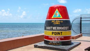 a boat sitting on top of a beach with Southernmost point buoy in the background