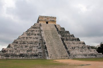a large stone building with Chichen Itza in the background