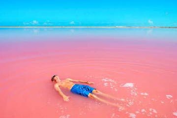 a person swimming in a body of water with Lake Retba in the background