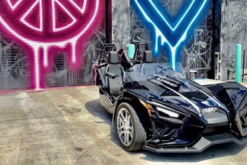 a slingshot parked in front of a graffiti wall