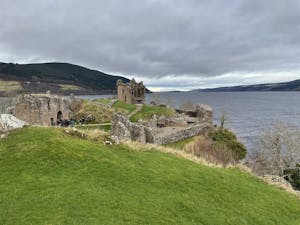 a castle on top of a grass covered field with Urquhart Castle in the background