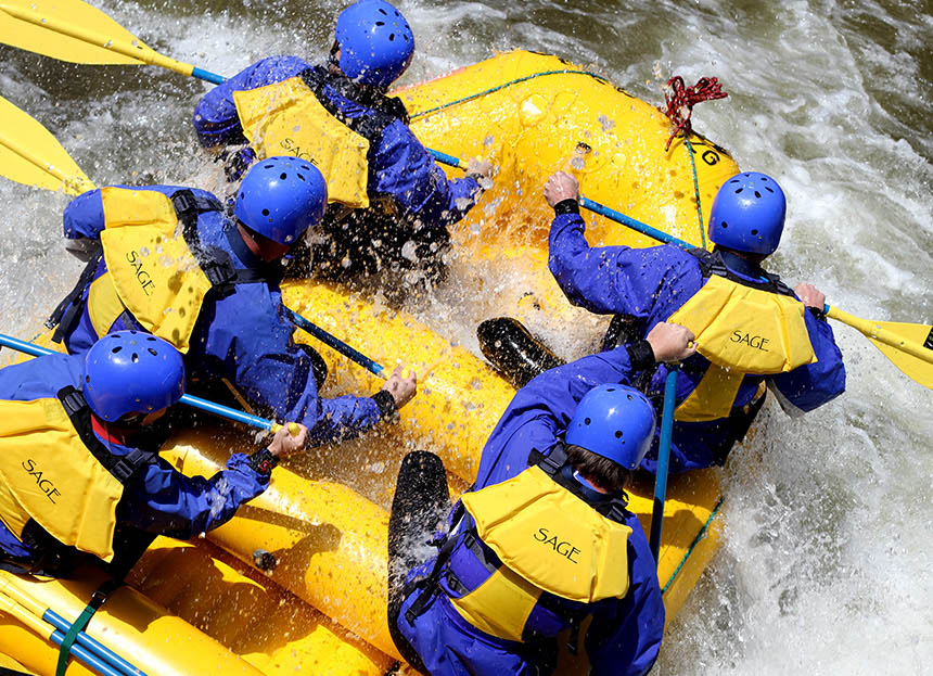 aerial view of five people in blue and yellow whitewater rafting