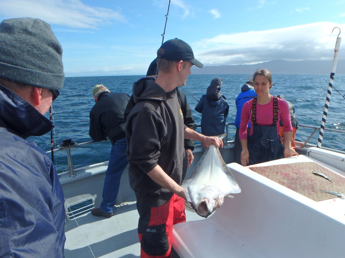 Rainbow Tours fishing staff holding a halibut on the boat