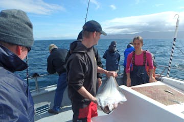 Rainbow Tours fishing staff holding a halibut on the boat