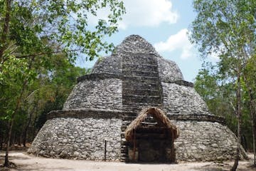 a stone building that has a large rock with Coba in the background