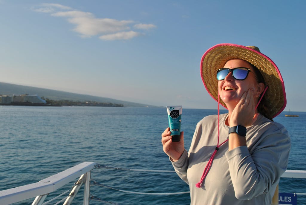 a person wearing a hat and sunglasses in front of a body of water