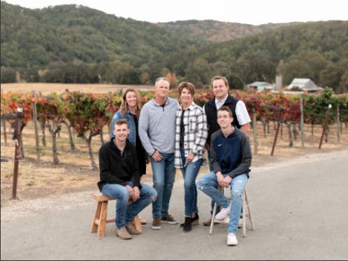 family standing in front of a vineyeard