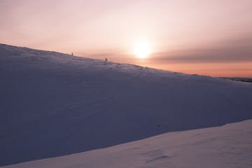 a sunset over a snow covered slope