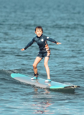 a boy riding a wave on a surfboard in the water