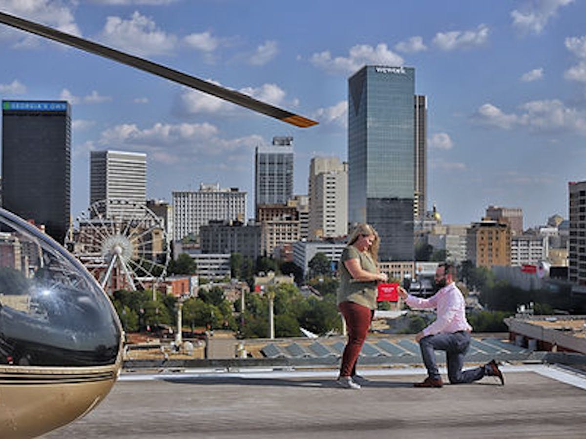 a man proposing to a woman with a helicopter at its background