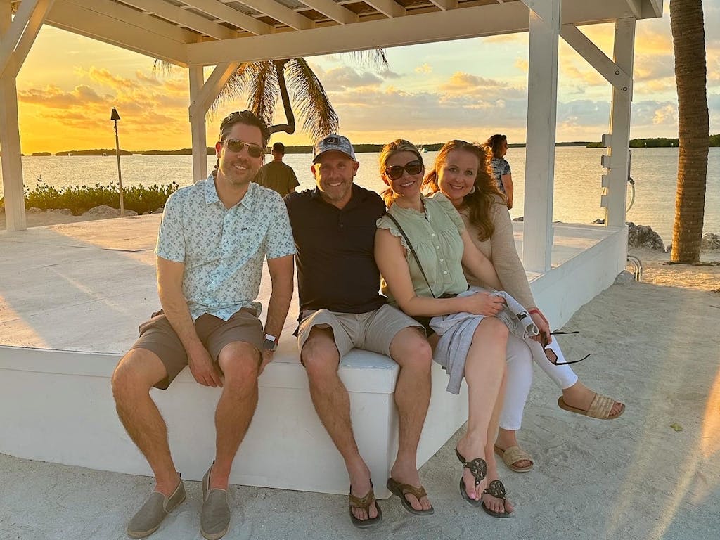 a couple of people that are sitting on a bench posing for the camera at sunset over the florida bay in islamorada florida keys