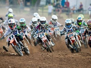 a group of people riding a motorcycle on a dirt track