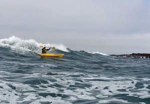 a person riding a wave on a kayak in the ocean