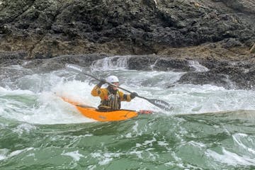 a man riding a wave on a kayak in the water