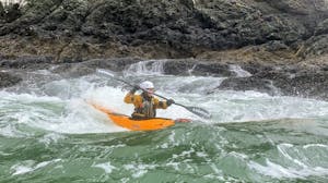 a man riding a wave on a kayak in the water