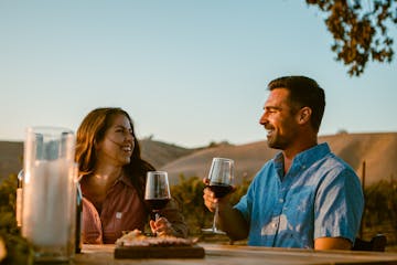 a couple enjoying a glass of wine during their private picnic in wine country
