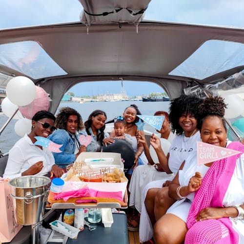 a group of ladies on a small boat in amsterdam celebrating gender reveal party