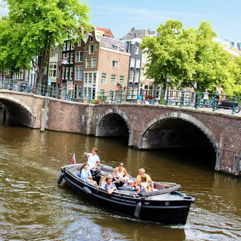 an open boat cruising across a bridge over an amsterdam canal