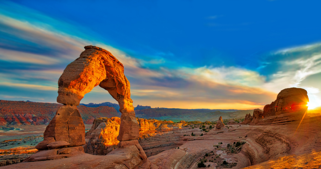 a canyon with a sunset in the background with Arches National Park in the background