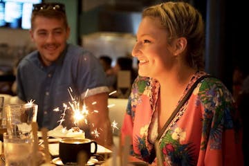 a person standing in front of a birthday cake with lit candles