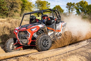 A Polaris RZR XP 4 1000 riding down a trail in the woods