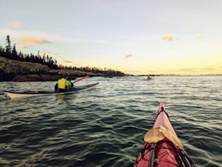 sea kayakers watch a winter sunrise on the water