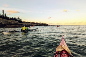 sea kayakers watch a winter sunrise on the water