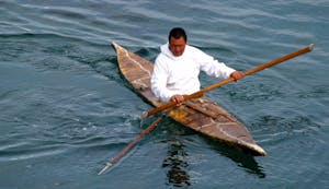 an indigenous Inuit man in a traditional kayak