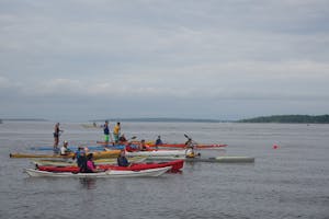 Kayakers and paddleboarders line up on the water for the start of a race