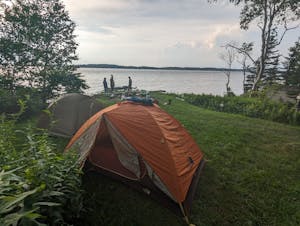 a tent in a grassy area next to a body of water