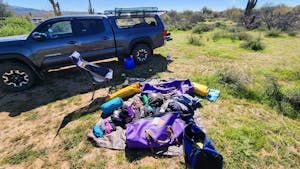 Rafting equipment being packed in a field, a pickup truck and cactuses in the background