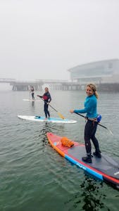 Three women on paddle boards on a foggy day