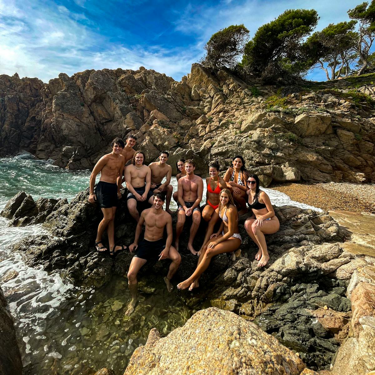 a group of people on a rock next to a body of water