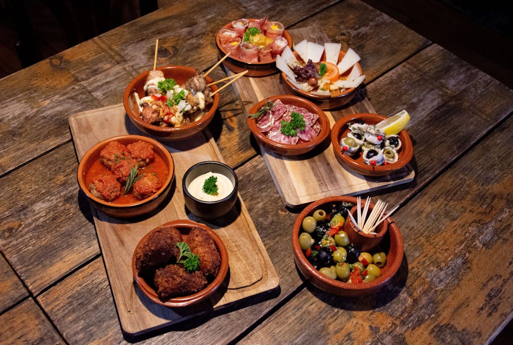 Wooden table topped with plates of tapas dishes.