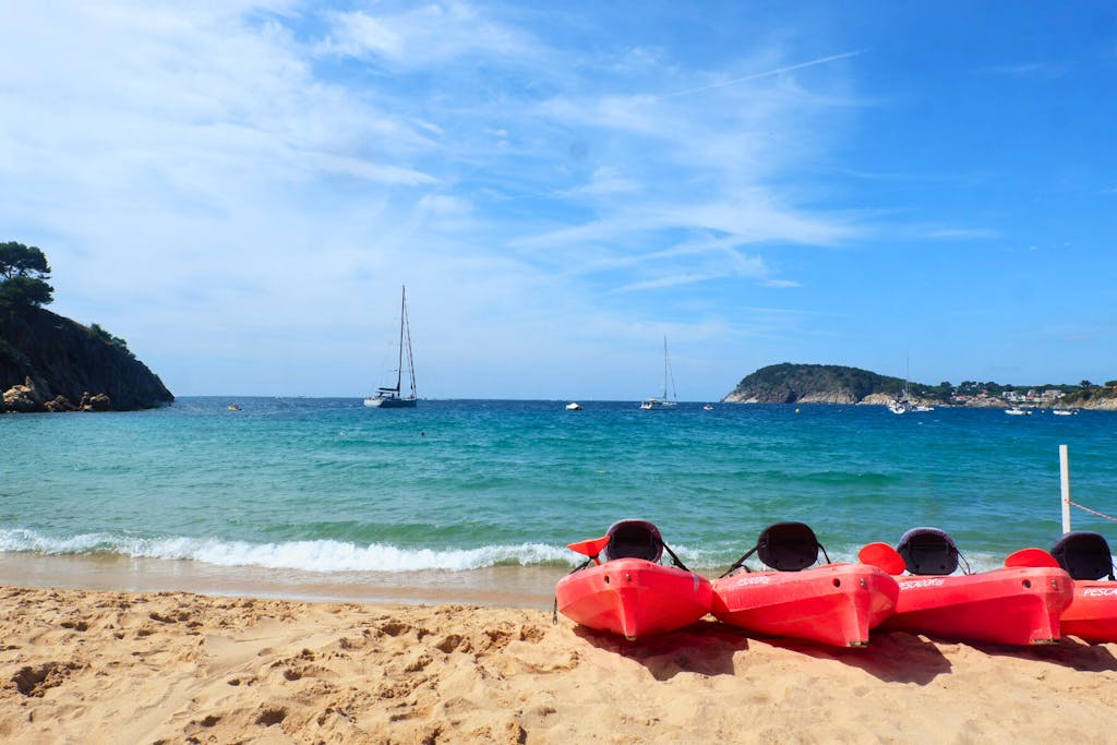 Kayaks sitting on top of a beach with blue water in the Costa Brava.