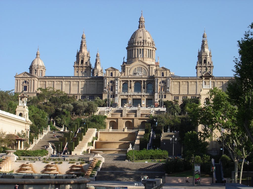 A large old building in Barcelona with a fountain.
