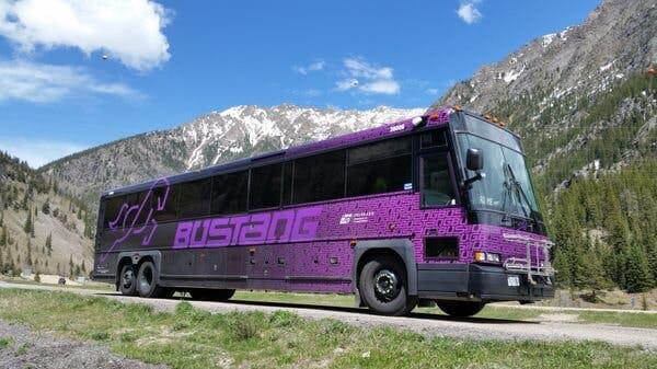 a large tour bus is parked on the side of a mountain