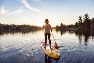 Adventurous Caucasian Adult Woman Paddling on a Stand up Paddle Board