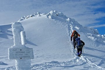 two people climbing up a snow covered mountain