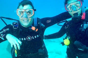 Two scuba divers smiling warmly at the camera, perfectly capturing the joy of underwater exploration in Kauai, Hawaii with Fathom Five Divers