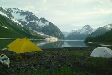 a tent in a body of water with a mountain in the background