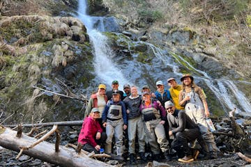 a group of people standing next to a waterfall