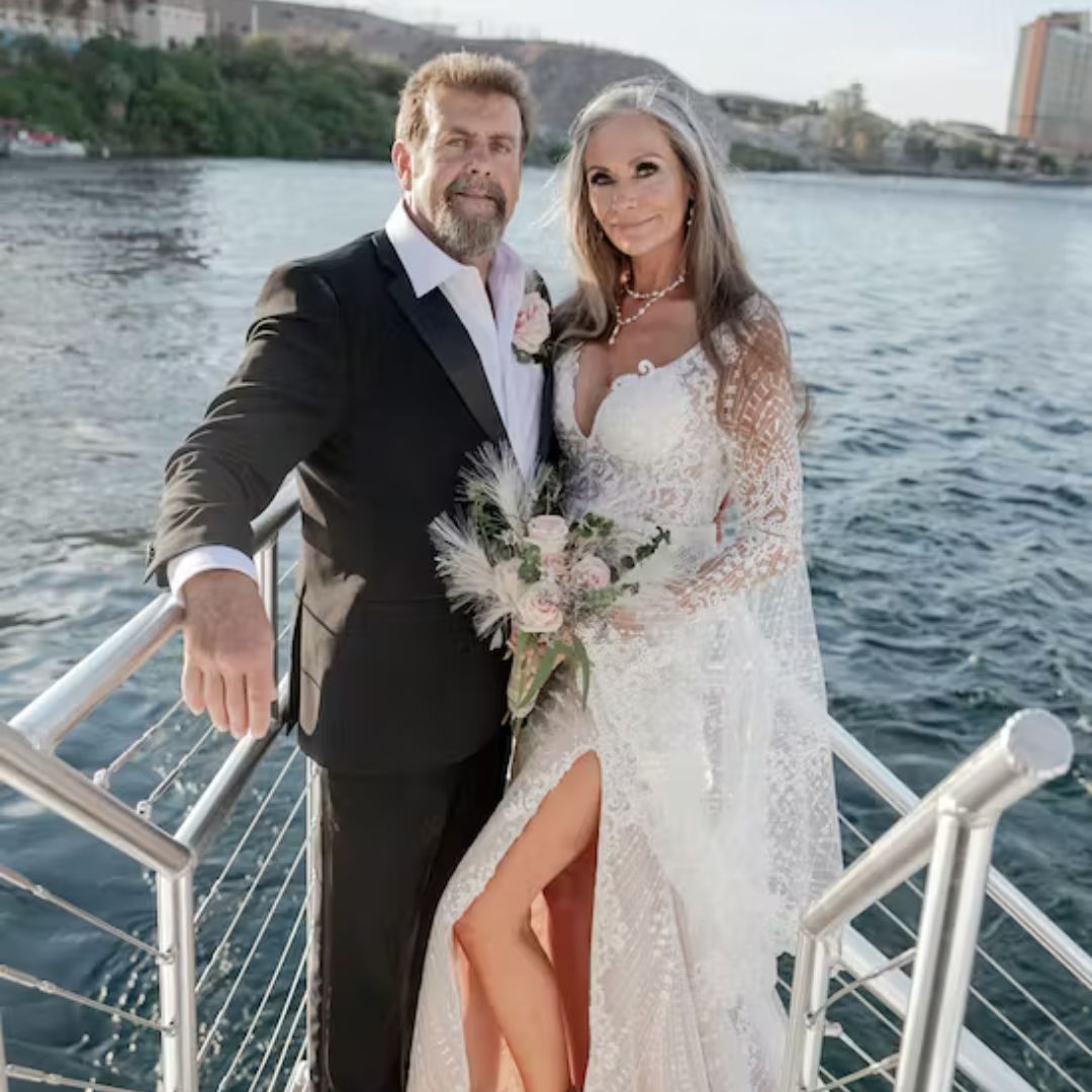 a married couple standing next to a body of water